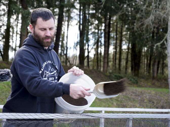 Kevin Hoffman, career and technical education teacher at Onalaska High School in Onalaska, Washington, feeds fish at Carlisle Lake as part of the school's aquaculture program on March 5, 2024. He was able to dramatically grow the program with help from two TransAlta grants. (Jeremy Long - WITF)