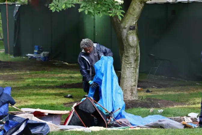 A worker clears away a tent on Penn's college green.