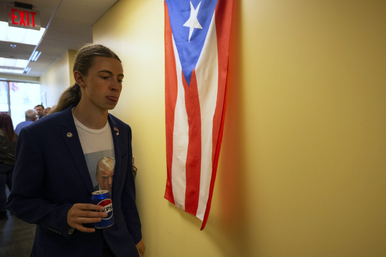 Bode Brewer, 17, wears a shirt featuring former President Donald Trump's mugshot as as the "Latino Americans for Trump" office opens in Reading, Pa., Wednesday, June 12, 2024. (AP Photo/Joe Lamberti)