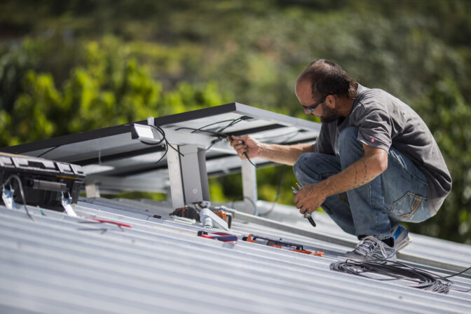 FILE - A technician installs a solar energy system at a home July 24, 2018, in Adjuntas, Puerto Rico. A U.S. government ongoing study that released preliminary results Monday, Jan. 23, 2023, has determined that with little room on the island for large-scale solar farms or wind generators, Puerto Rico should aim to reach its clean-energy goals by installing solar panels on all suitable rooftops, along with airports, brownfields and industrial areas. (AP Photo/Dennis M. Rivera Pichardo, File)