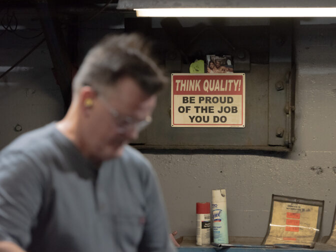 A sign hangs on the wall while a Scranton Army Ammunition Plant employee performs a hot inspection of metal parts in Scranton, PA, on August 27, 2024.