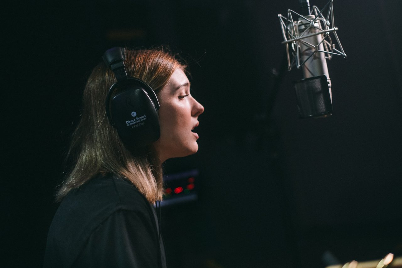 An image of Olivia Elizabeth Basar singing into a microphone.