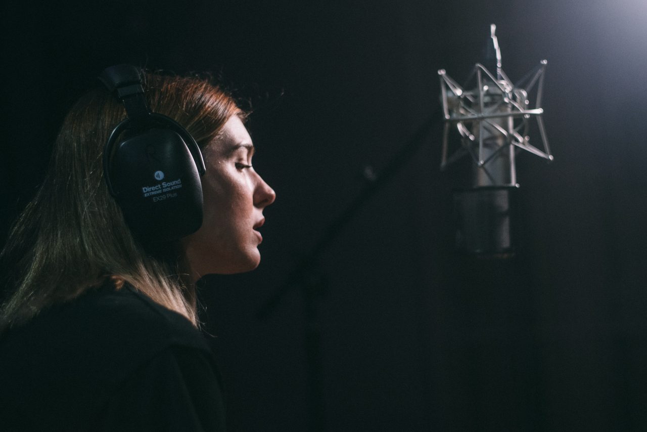 An image of Olivia Elizabeth Basar singing into a microphone.
