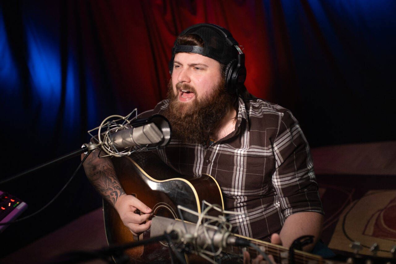 Jake Mach singing and playing guitar.