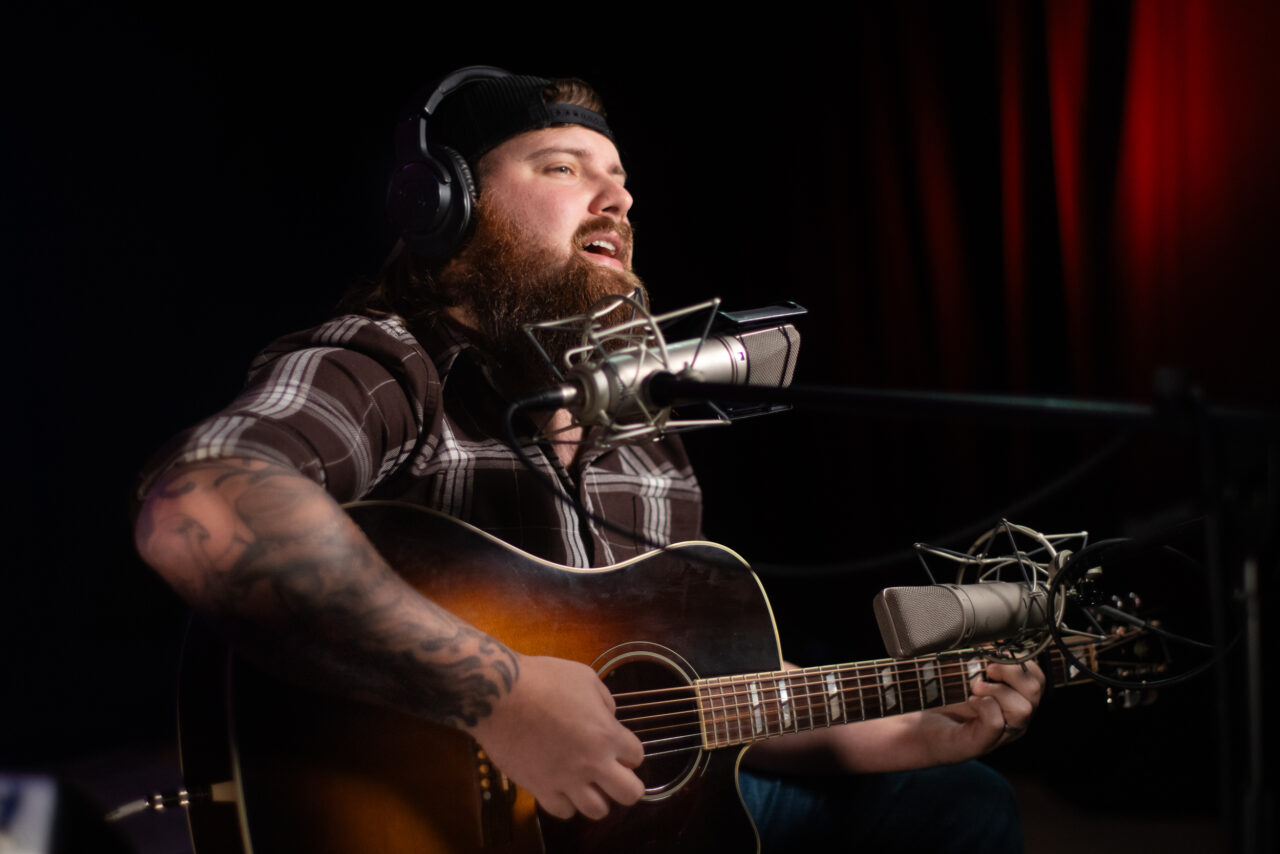 Jake Mach singing and playing guitar.