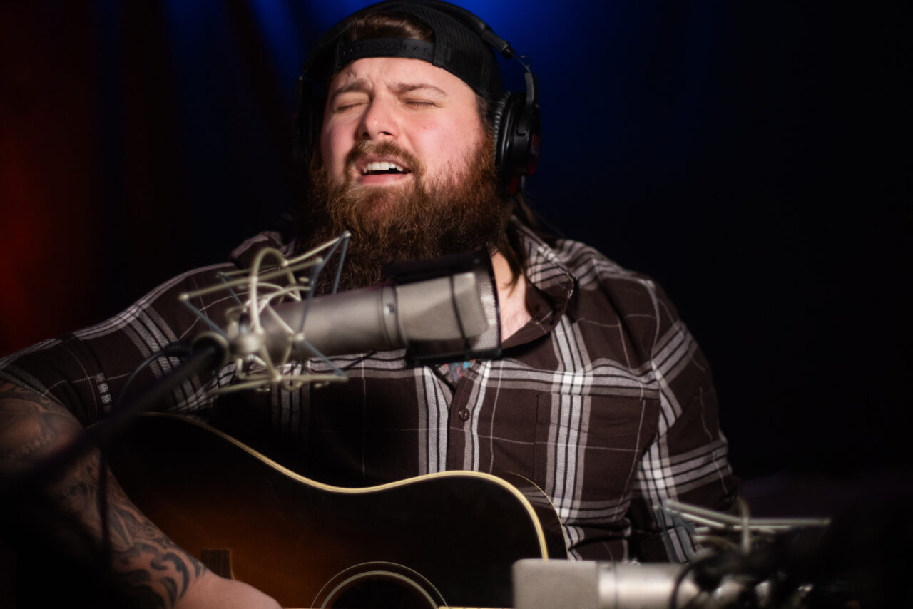 Jake Mach singing and playing guitar.