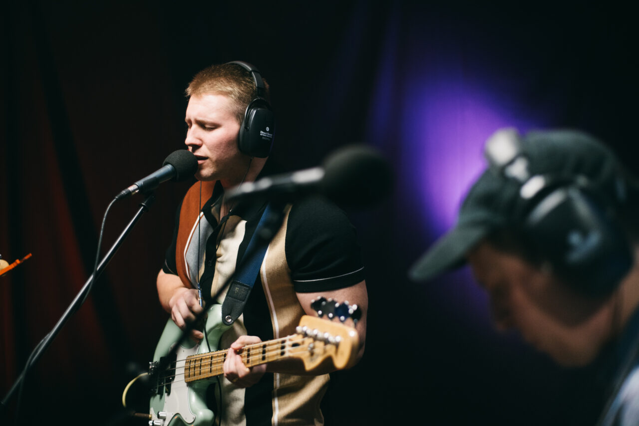 A person playing bass guitar and singing.