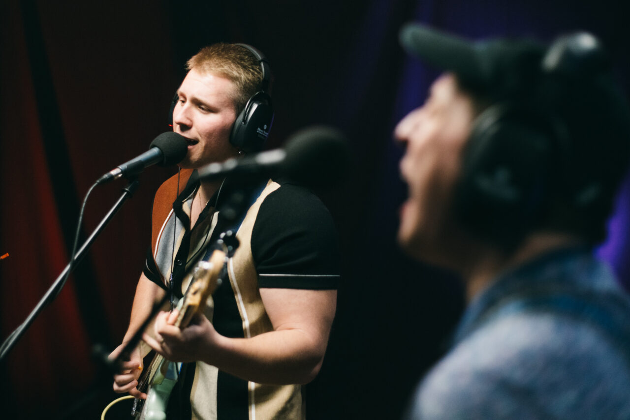 A person playing bass guitar and singing.