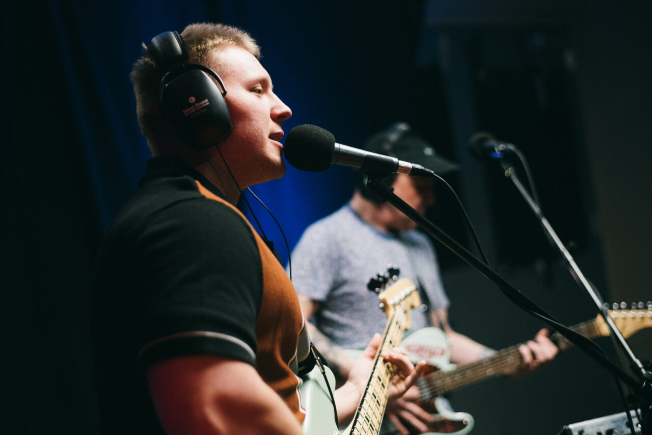 A person playing bass guitar and singing.